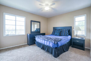 bright carpeted bedroom with blue bed