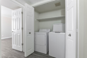 Interior unit laundry closet, wood floors, closet with washer and dryer, shelf for laundry utilities.